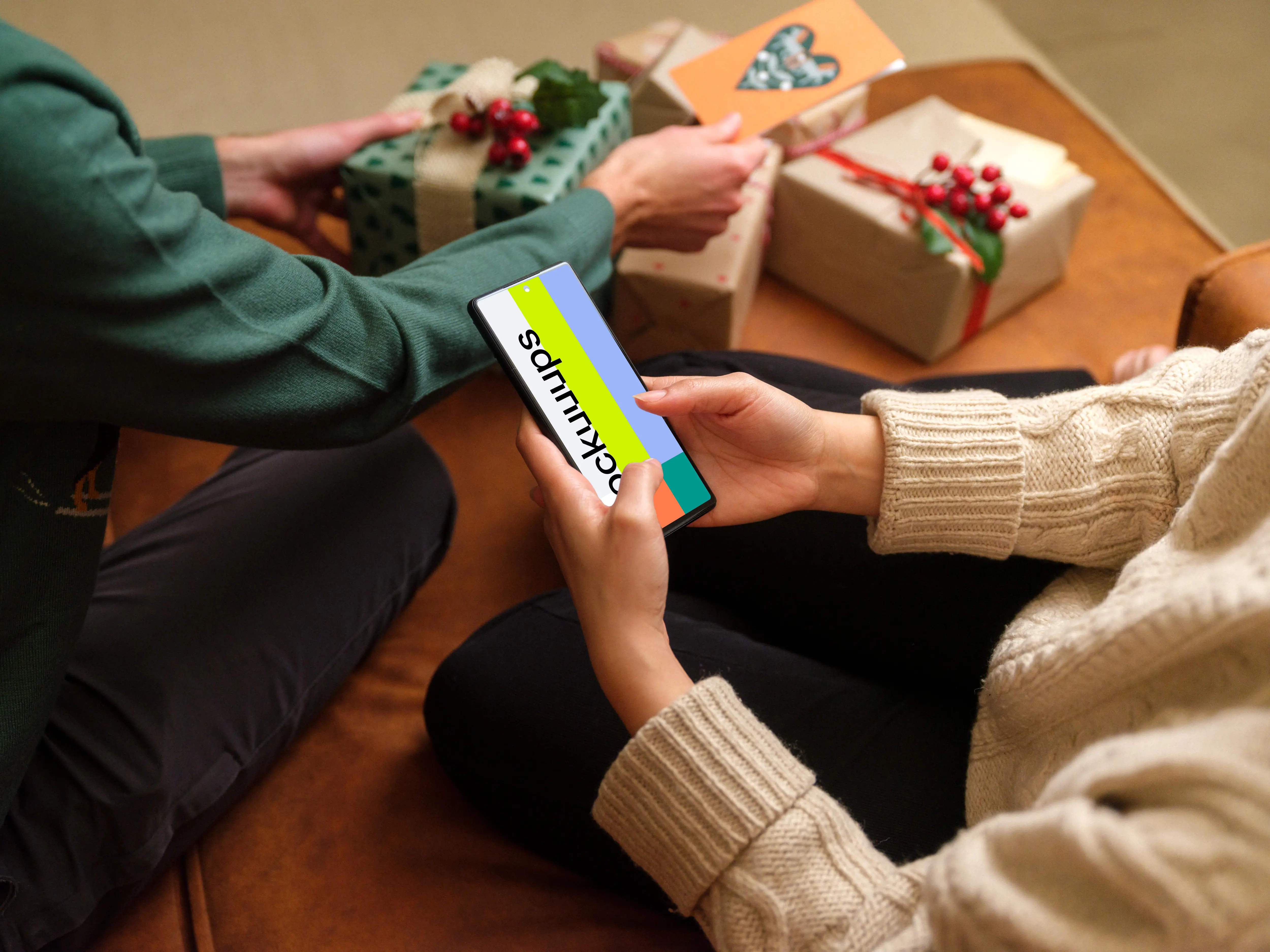 Woman typing on a phone mockup next to the Christmas gifts