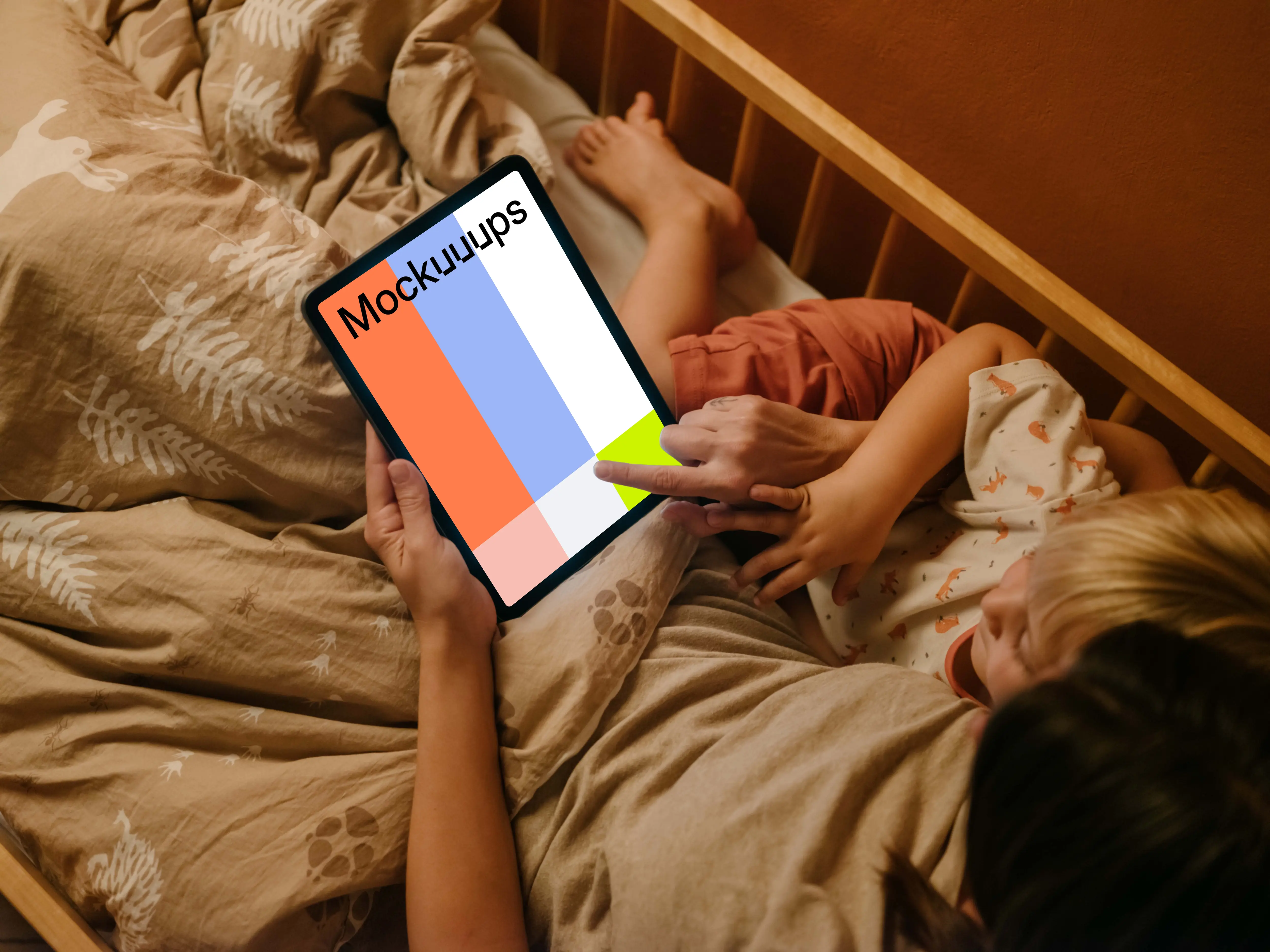 Woman with a child typing on an iPad mockup in bed
