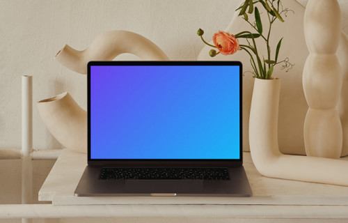 MacBook mockup on a peach colored table with a fancy flower vase