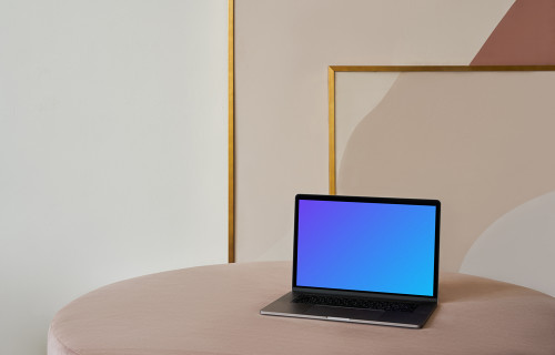 MacBook mockup on a table with a beautiful painting behind it