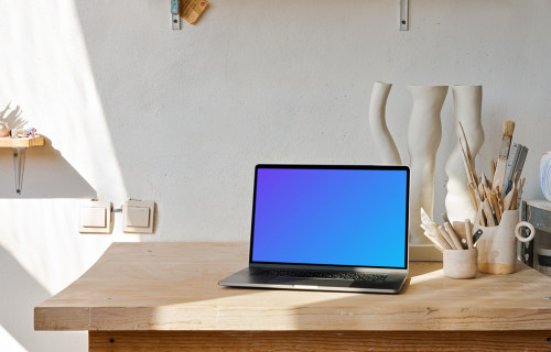 MacBook mockup on a wooden table with wooden art craft at the side