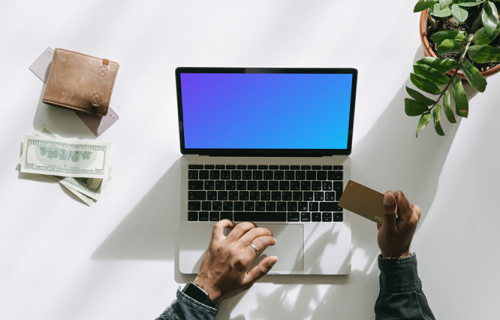 Mockup of User shopping on a Grey MacBook beside some cash and a wallet