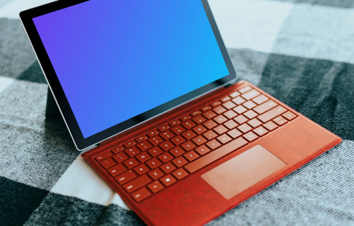 Red Microsoft Surface Laptop mockup on a bed