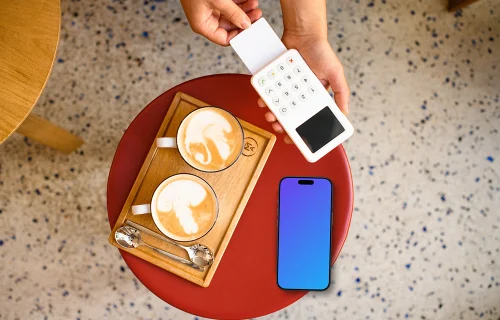 Cozy cafe setting with payment terminal and an iPhone mockup