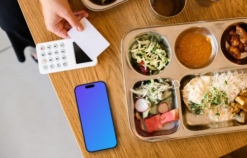 Assiette de nourriture à côté de l'iPhone mockup et du terminal de paiement