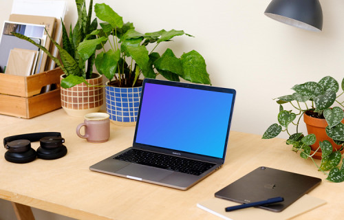 Grey MacBook Pro on a table with plants in the background