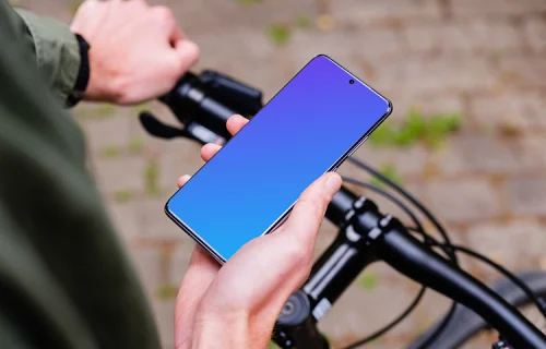 Tenant le vélo d'une main et le Samsung S20 mockup de l'autre