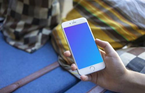 Holding iPhone 6 mockup on a Sofa with Pillows