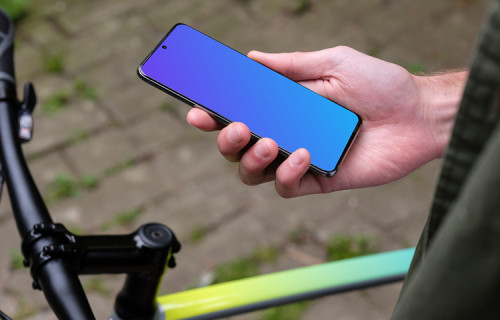 Sosteniendo el Samsung S20 mockup en una mano junto a una bicicleta