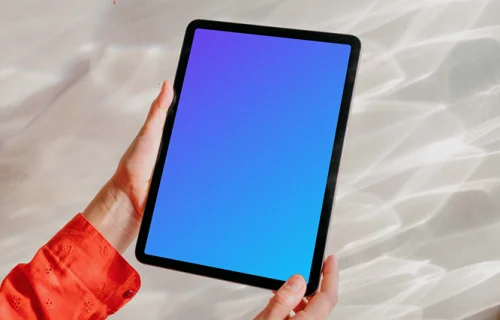 iPad Air gratuit mockup tenu par l'utilisateur sur un fond argenté brillant 