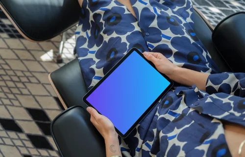 iPad Air mockup in a woman's hand on a modern chair