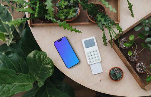 iPhone mockup em meio a uma vegetação exuberante com terminal de cartão
