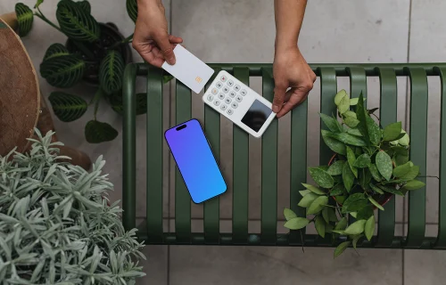iPhone mockup con terminal de tarjeta de crédito entre plantas