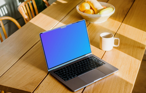 MacBook mockup beside a coffee mug and fruit basket