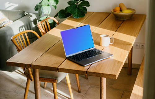 MacBook mockup on a table beside a coffee mug
