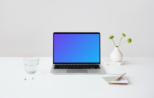 MacBook mockup on a table with glass of water at the side