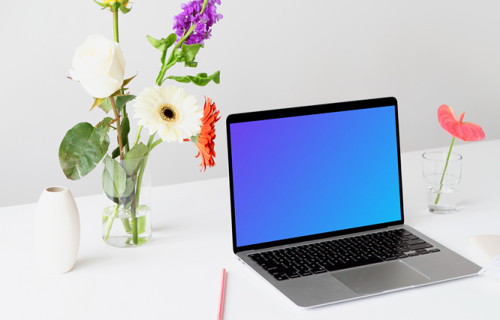 MacBook mockup sur une table blanche avec de belles fleurs dans un vase transparent