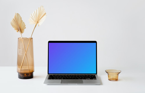 MacBook mockup on a white table with fancy flower vase at the side