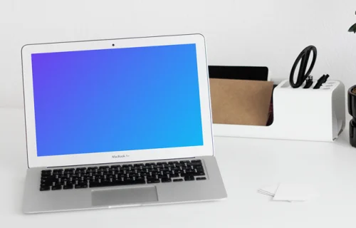 MacBook mockup on a white table with writing materials on the side