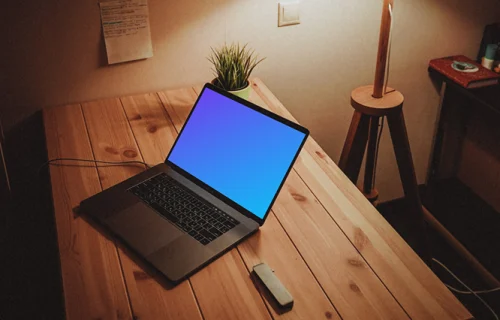 MacBook night mockup on a wooden table with a lamp by the side