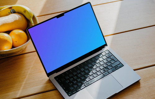 MacBook Pro mockup on a table in front of a basket of fruits