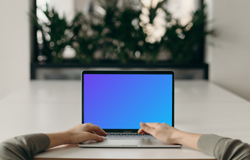 MacBook Pro mockup on a white table opposite an large mirror