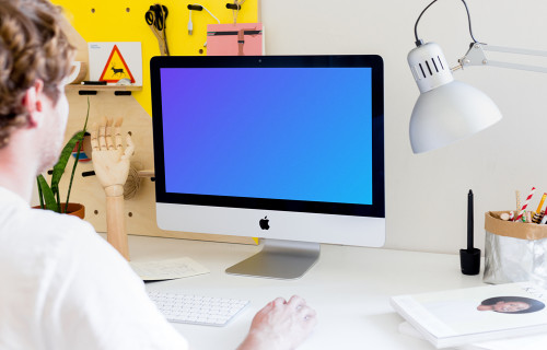 Homem trabalhando no iMac mockup (Angle View)