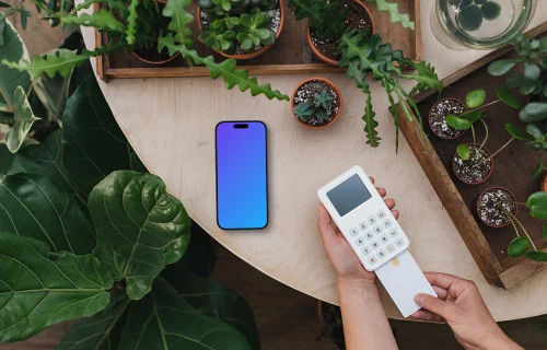 Terminal de paiement et iPhone mockup entourés de plantes