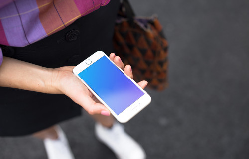 Woman holding iPhone 7 mockup on the street