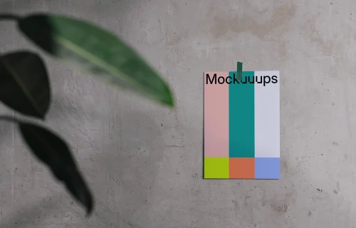 A4 mockup taped to a concrete wall with a plant in the foreground