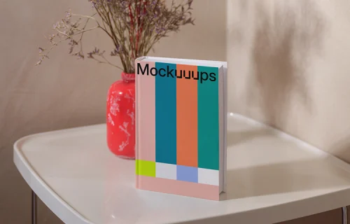 B-format book mockup on a white table with a red vase