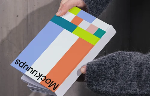 Book mockup held against a concrete wall