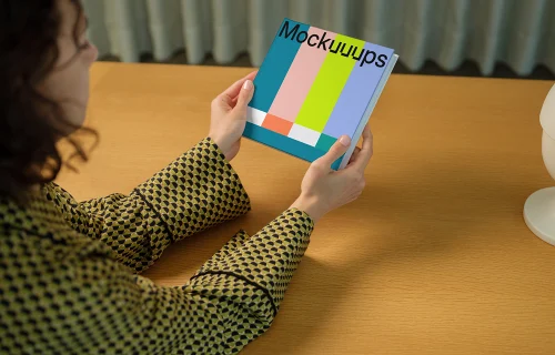 Book mockup held by a person at a wooden desk