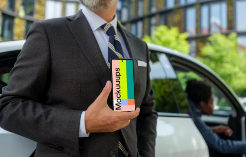 Businessman standing next to the Tesla and holding a phone mockup
