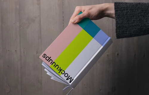 C-format book mockup held against wooden wall