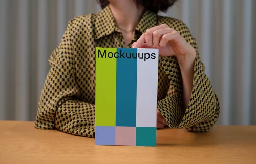 C-format book mockup held by person on wooden table