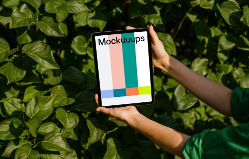 Female holding an iPad Air mockup in front of plant leaves