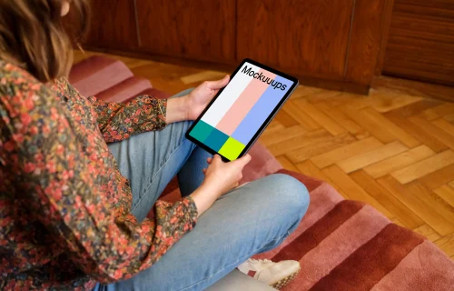 Female holding iPad mockup against a wooden background in the lounge