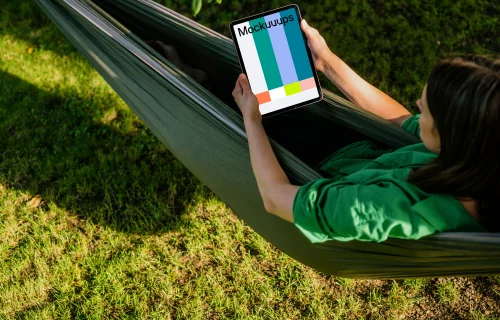 Female laying in hammock while holding a tablet