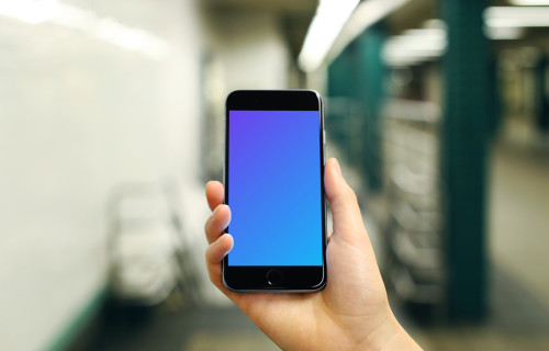 Holding iPhone 6s mockup on a Train Station