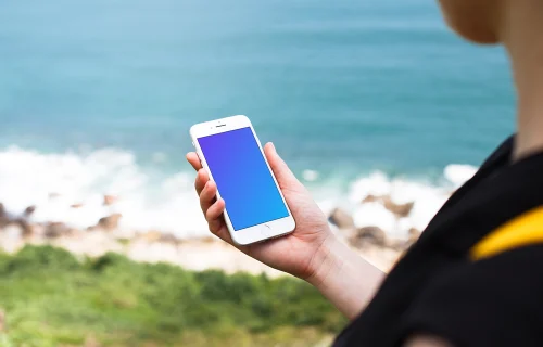 Holding iPhone 7 mockup next to the ocean