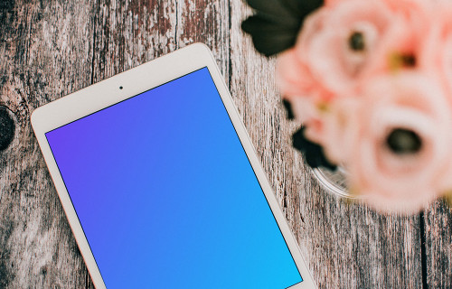 iPad Mini mockup a brown table beside a vase of roses