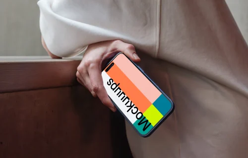 iPhone 16 mockup held by a person near a concrete surface