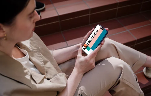 iPhone 16 mockup held by a woman on outdoor steps