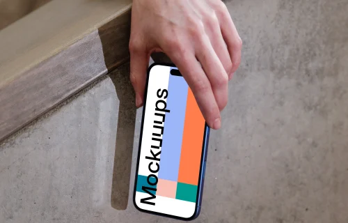iPhone 16 mockup held by hand against concrete