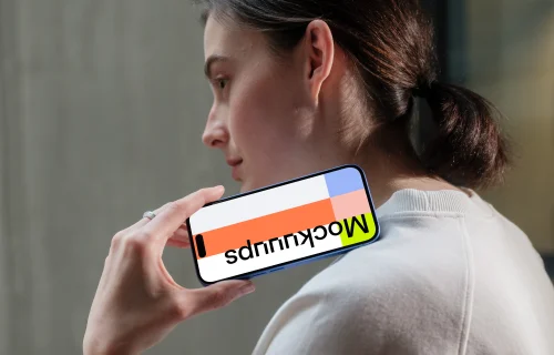 iPhone 16 mockup held by woman near concrete wall