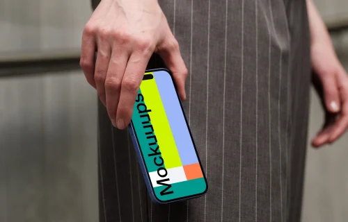 iPhone 16 mockup in hand with pinstripe pants