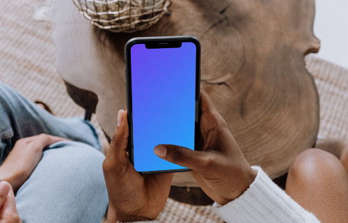 iPhone mockup held above a wooden table