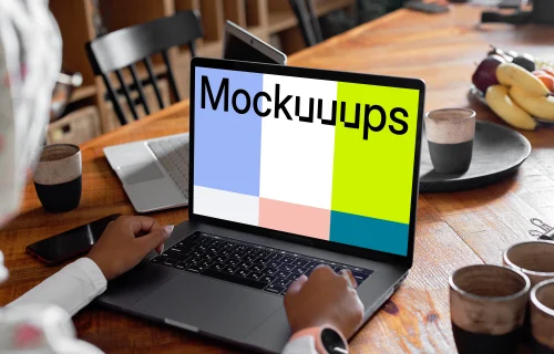 MacBook Air mockup in use by a lady with coffee mugs at the side 