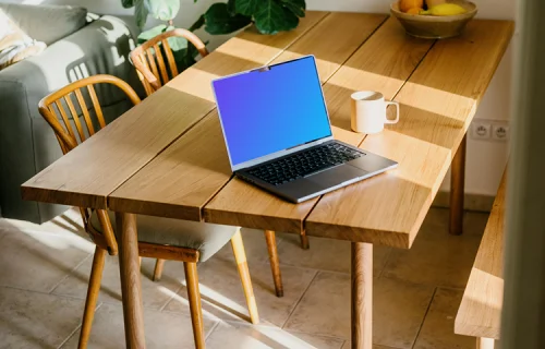 MacBook mockup on a table beside a coffee mug
